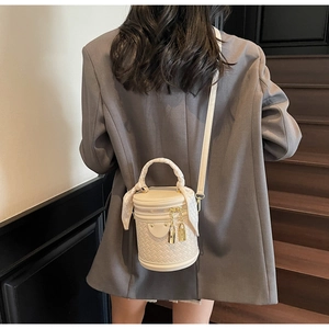 Detail of cream woven bucket bag with gold lock charms and silk scarf handle