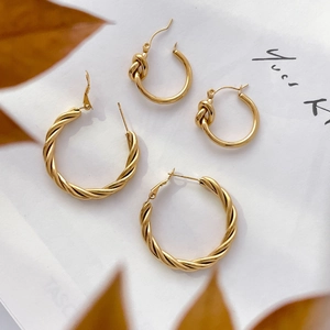 Textured twist hoop and knot C-shaped gold earrings set on a minimalist background