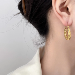Macro view of 18K gold-plated twisted rope texture on C-shaped hoop earrings