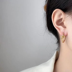 Detailed close-up of 18K gold plated titanium steel twisted rope knot hoop earring
