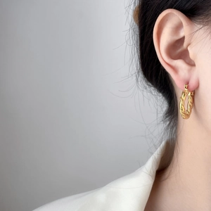 Close-up of golden twist rope earrings in 18K gold plated titanium on model
