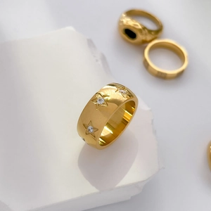 Détail macro d'une bague large plaquée or 18 carats avec étoiles gravées et zircons blancs