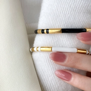 Minimalist twisted rope bangle set with black and white enamel in gold finish on wrist