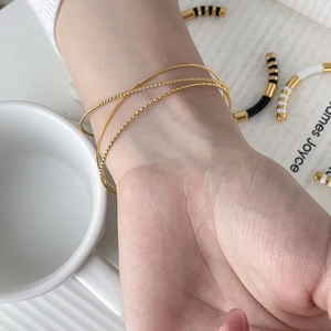 Three-piece gold thin bangle set featuring minimalist twisted rope and smooth finish textures