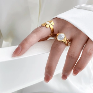 Detail of gold floral daisy ring and oval mother of pearl stone ring on hand