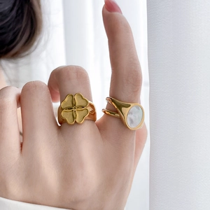 Golden flower and oval mother of pearl shell rings set on model hand with minimalist style