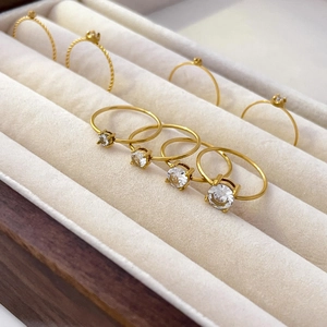 Macro view of gold-plated twist rings with four-prong set round cubic zirconia in a jewelry box