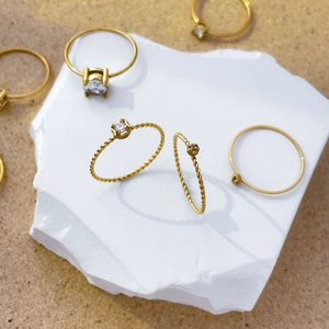 Detail of 18K gold plated twist band rings featuring a four-prong set cubic zirconia stone