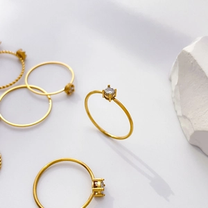 Macro detail of 18K gold plated thin ring set featuring four-prong zircon on white stones