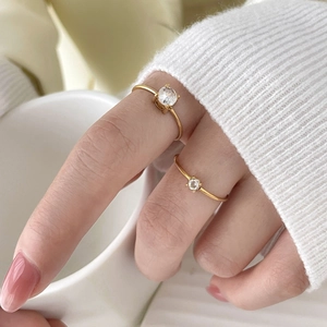 Close-up of gold twist rings featuring four-prong cubic zirconia in a lifestyle setting