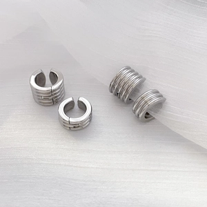 Detail showing two styles of silver geometric ear cuffs on white textured mesh background