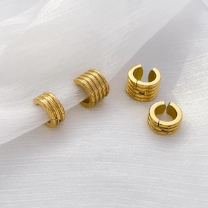 Detail of 18K gold-plated titanium steel ribbed ear cuffs on white mesh fabric