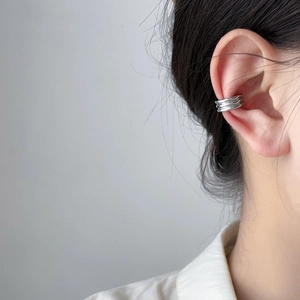Close-up of a silver minimalist multi-layer ear cuff worn on ear with a sleek metal finish