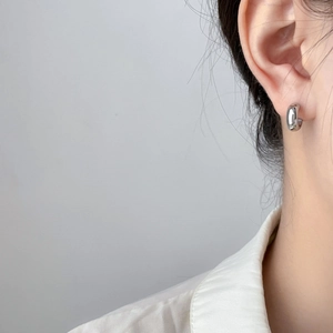 Close-up of a model wearing a polished silver geometric C-shaped stud earring