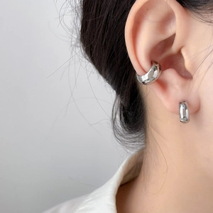 Close-up of a silver polished wide ear cuff and minimalist hoop earring on ear
