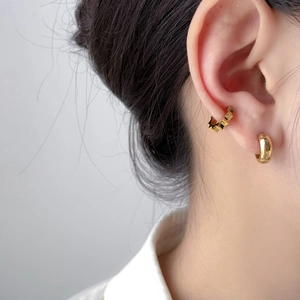 Detail of 18K gold-plated C-shaped hoop earring and geometric gear-shaped ear cuff