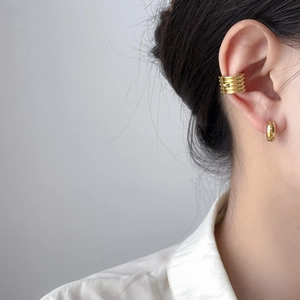 Close-up of stacked gold ear cuff and polished small hoop earring on model ear