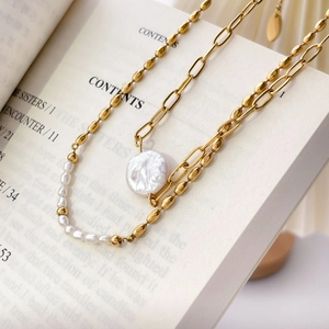 Detailed close-up of layered 18K gold plated pearl necklace on vintage book pages
