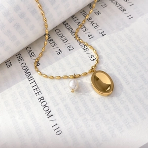 Detailed macro view of 18K gold plated necklace with rice beads, oval pendant, and pearl