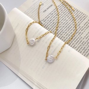 Macro detail of 18K gold paperclip chain and baroque pearl on an open book