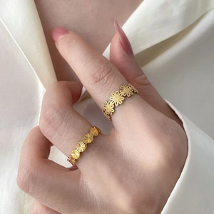 Détail de bagues marguerites et ovales plaquées or 18K sur fond de satin blanc