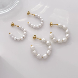 Elegant 18K gold plated C-shaped earrings set with dangling white pearls on white background