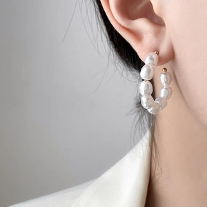 Close-up of C-shaped hoop earrings with three baroque pearls and 18K gold plating