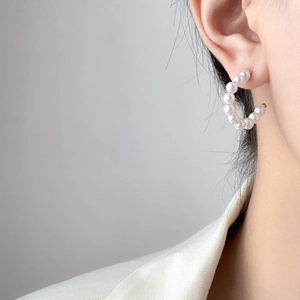 Detail of C-shaped hoop earrings with white pearls and 18K gold plated titanium steel