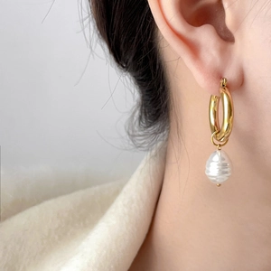 Detail of 18K gold plated C-shape hoop earring with a baroque pearl pendant on model