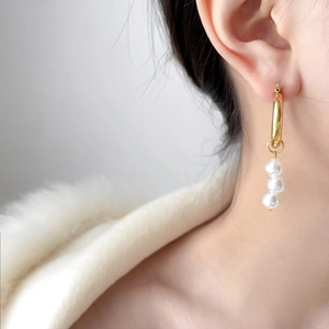 Detailed close-up of 18K gold plated C-shaped earrings with three hanging white pearls