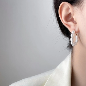 Close-up of elegant C-shaped pearl drop earrings in 18K gold plating on a model