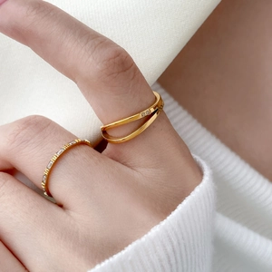 Nahaufnahme von goldener Doppelkreuz-Ring und Baguette-Zirkonia-Band an der Hand
