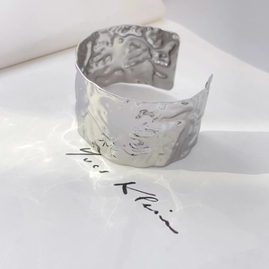 Macro view of wide silver cuff bracelet with hammer-textured surface and metallic finish