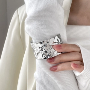 Silver wide liquid metal cuff bracelet with artistic crater texture on white knit sleeve
