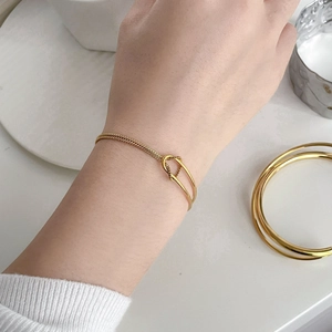 Close-up of minimalist gold snake chain bracelet with textured round ring on wrist