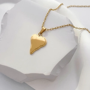 Vue détaillée d'un pendentif cœur en or 18 carats avec texture lave sur un socle pierre