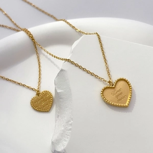 Détail macro du pendentif cœur plaqué or avec gravure Love You More et bord perlé