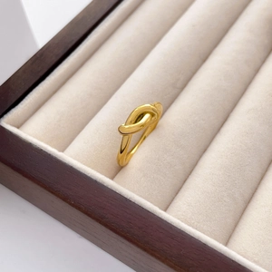 Detailed close-up of a twisted gold knot ring inside a premium jewelry box interior