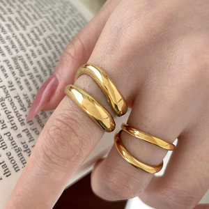 Close-up of three-piece 18K gold plated minimalist ring set worn on finger over book