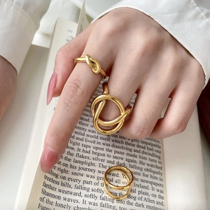 Detailed view of three gold-plated titanium steel rings with twisted knot and layered designs