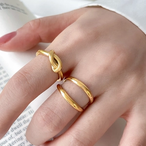 Detailed view of polished 18K gold-plated double-layer knot rings worn by a fashion model