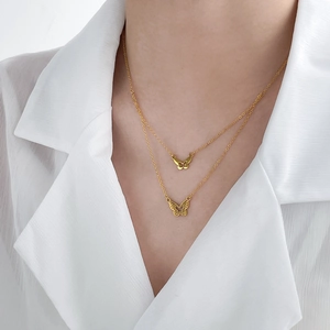 Gros plan d'un collier papillon double épaisseur doré avec motif floral en coquillage