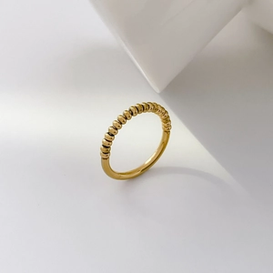 Close-up of 18K gold plated beaded wave ring with polished metal balls on white prop