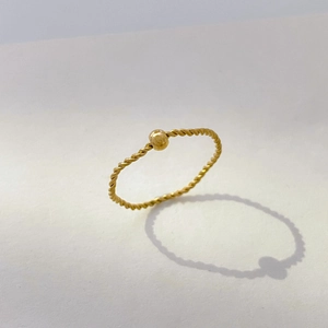 Detail of 18K gold plated titanium steel twist ring with a polished movable gold bead