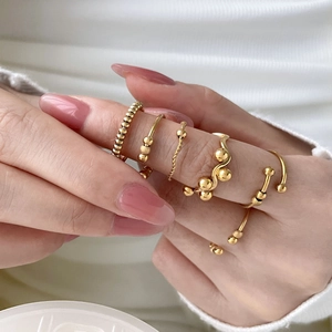 Set of 18K gold plated stackable rings with beaded and wave designs on a hand