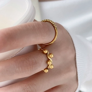 Close-up of wavy gold stackable rings with small beads on a woman's finger