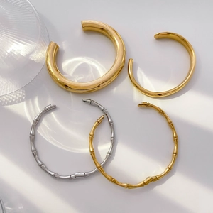 Set of four thick minimalist gold-plated bangles with bamboo texture on white background