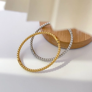 Close-up of gold and silver beaded titanium steel bangles on a wooden display stand