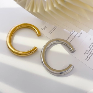 Detail of chunky hollow gold and silver bamboo style C-shaped open bangles on a poetic card