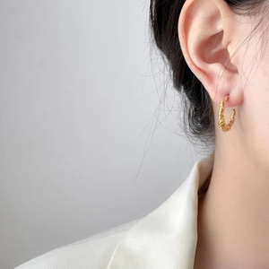 Golden C-shaped twisted rope earrings shown on model with elegant minimalist style